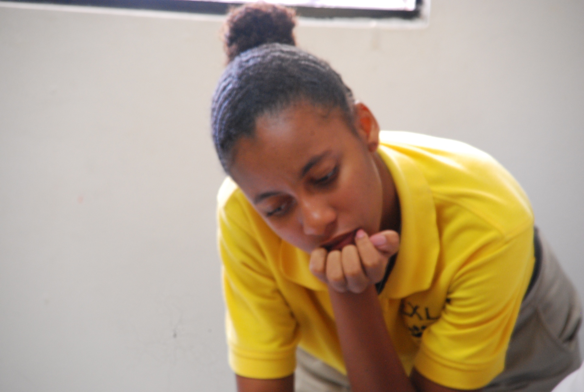 EXL student in yellow uniform polo resting during class