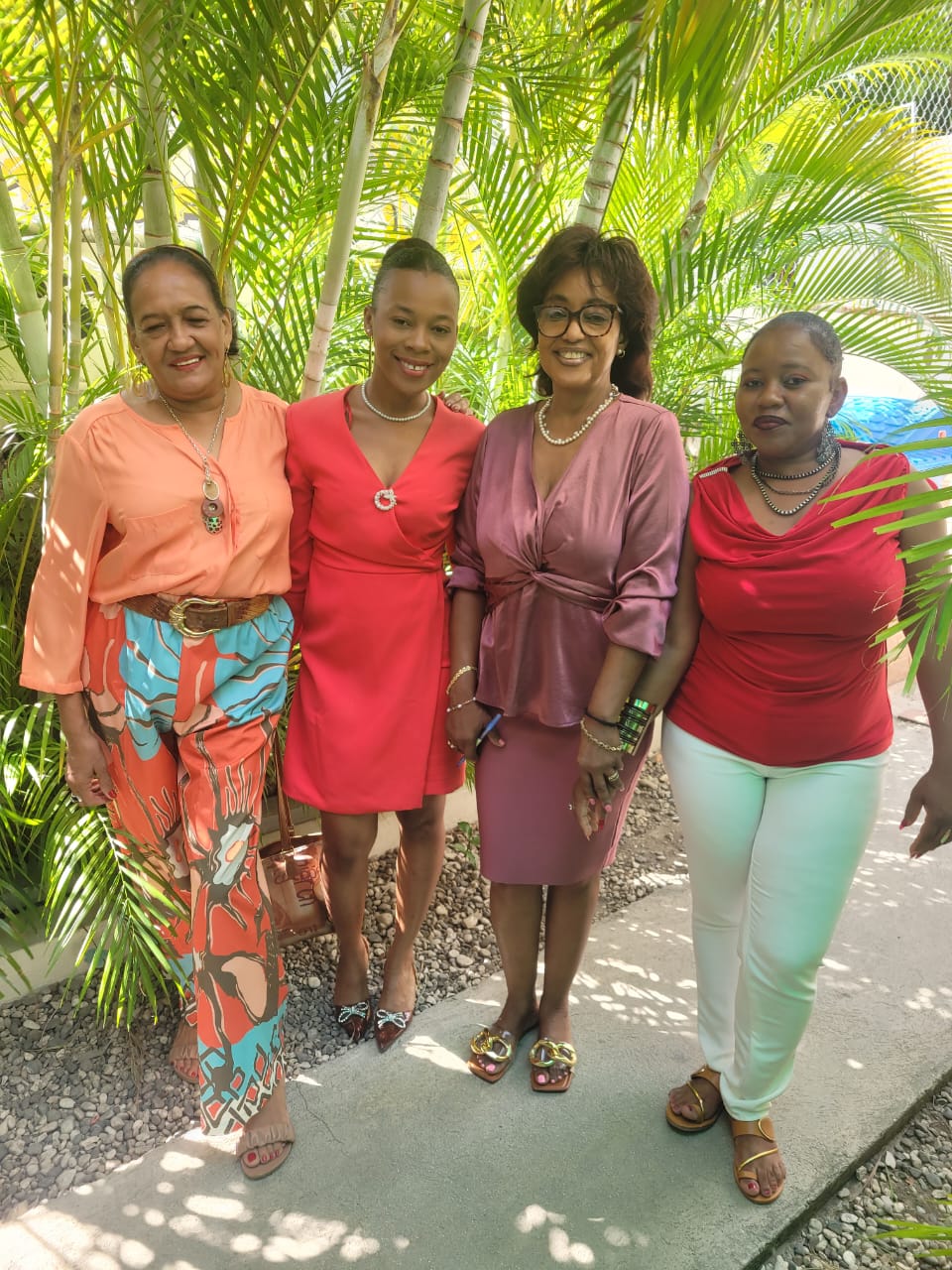 Four EXL staff members posing together in front of palm trees on campus
