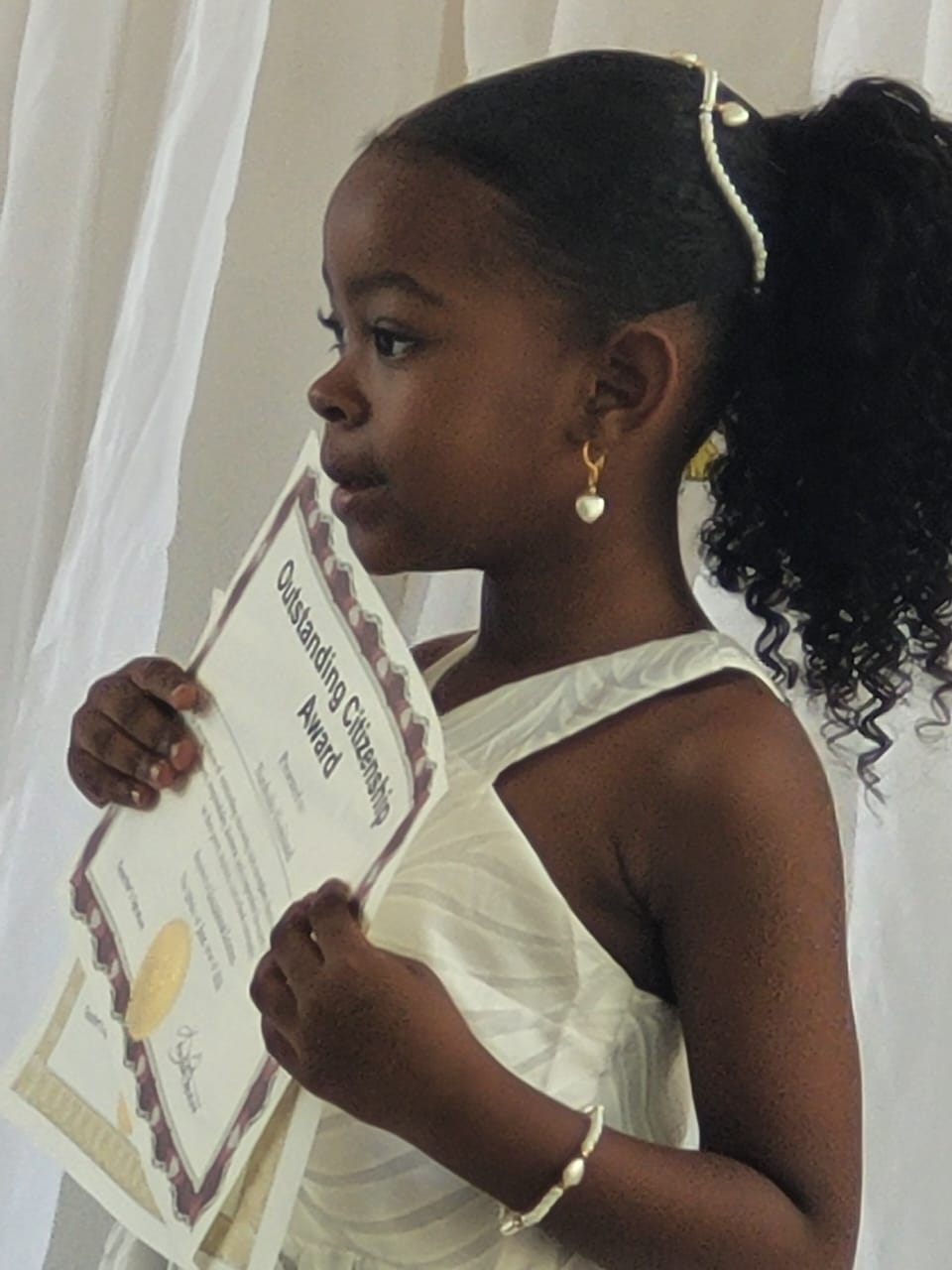 Young EXL student holding an Outstanding Citizenship Award certificate