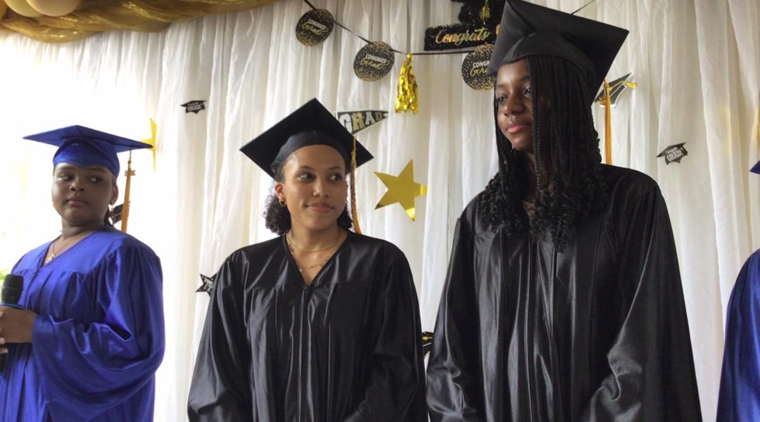EXL high school graduates in black caps and gowns
