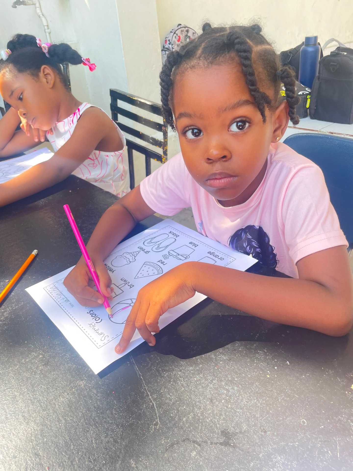 Young EXL summer camp student coloring a 'Summer Colors' worksheet