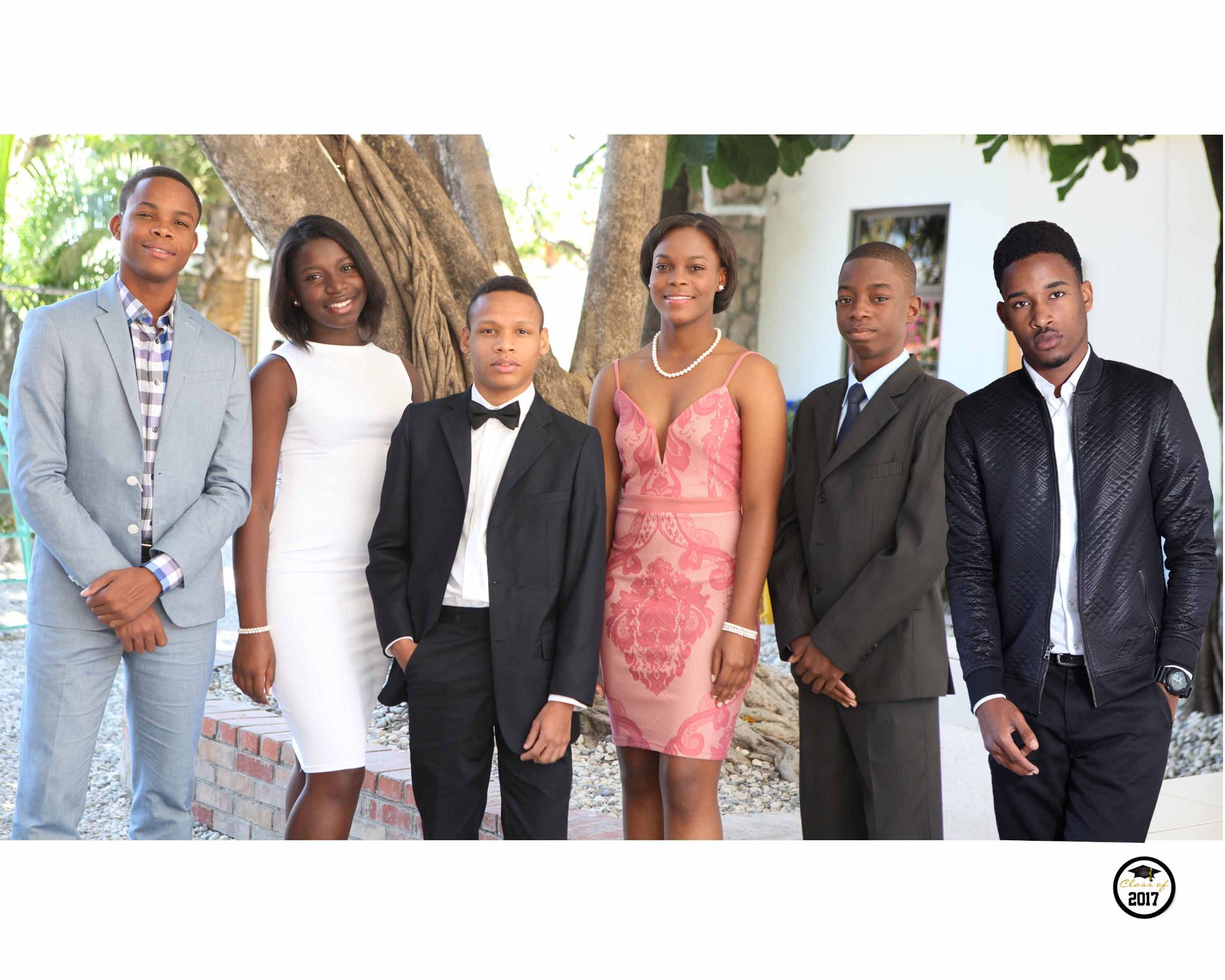 Six EXL graduates dressed elegantly for their graduation portrait under a large tree