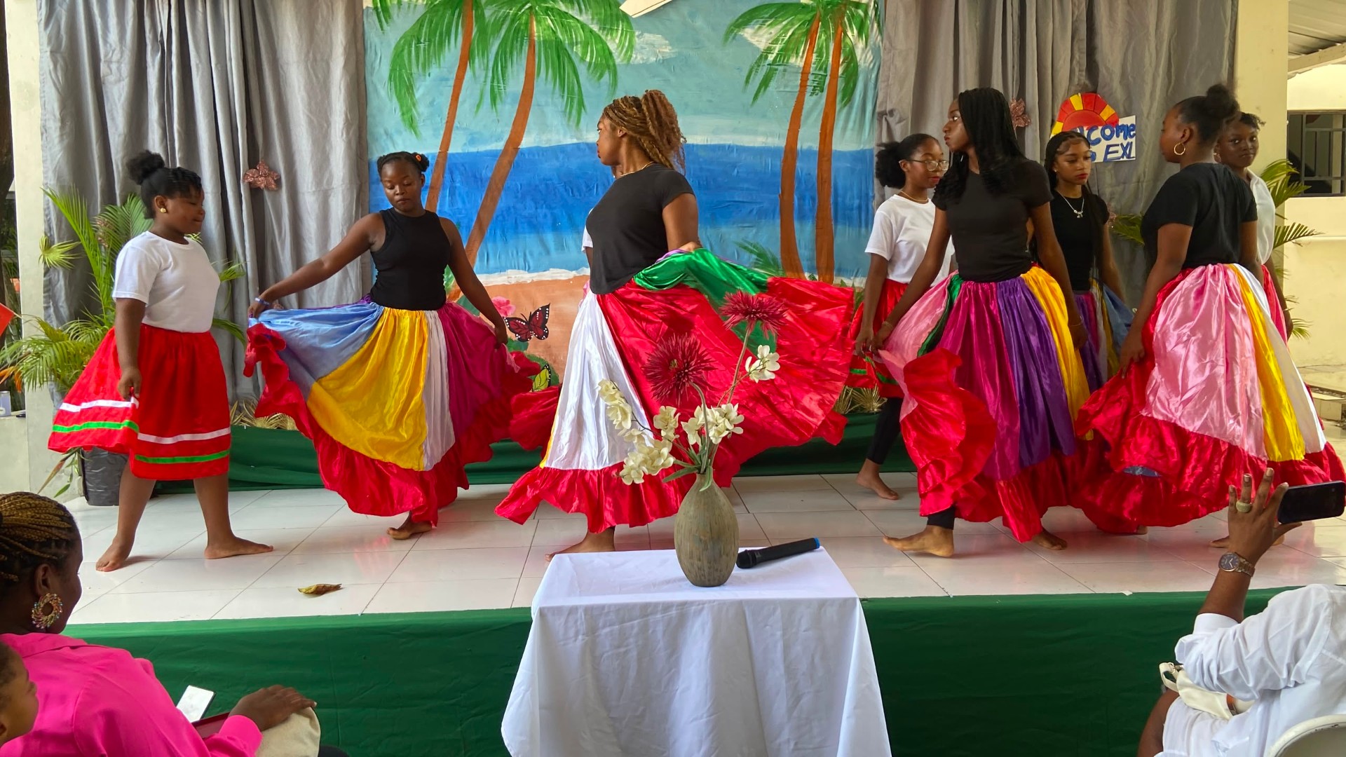 EXL students performing a traditional Haitian folk dance in colorful skirts