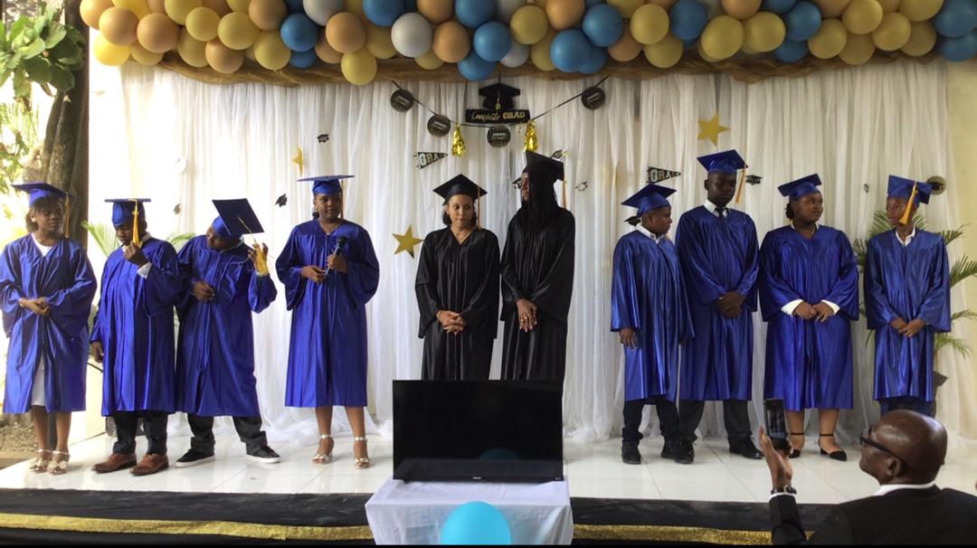 EXL graduates in blue and black caps and gowns lined up on stage
