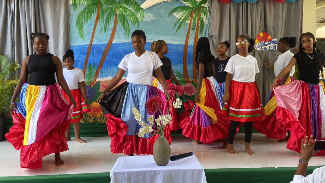 EXL students in colorful traditional skirts dancing on stage