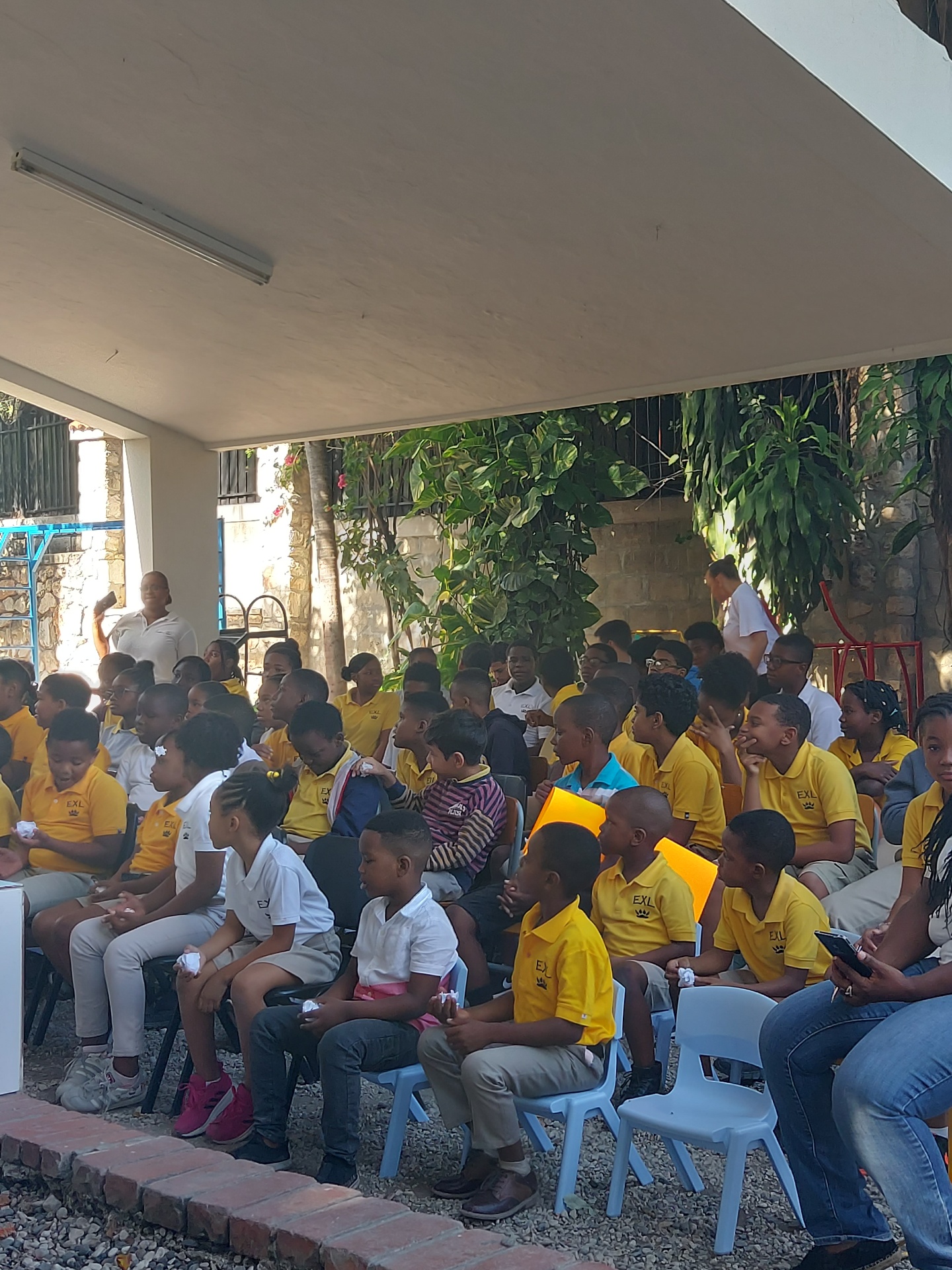 EXL students in yellow uniforms gathered for an outdoor assembly