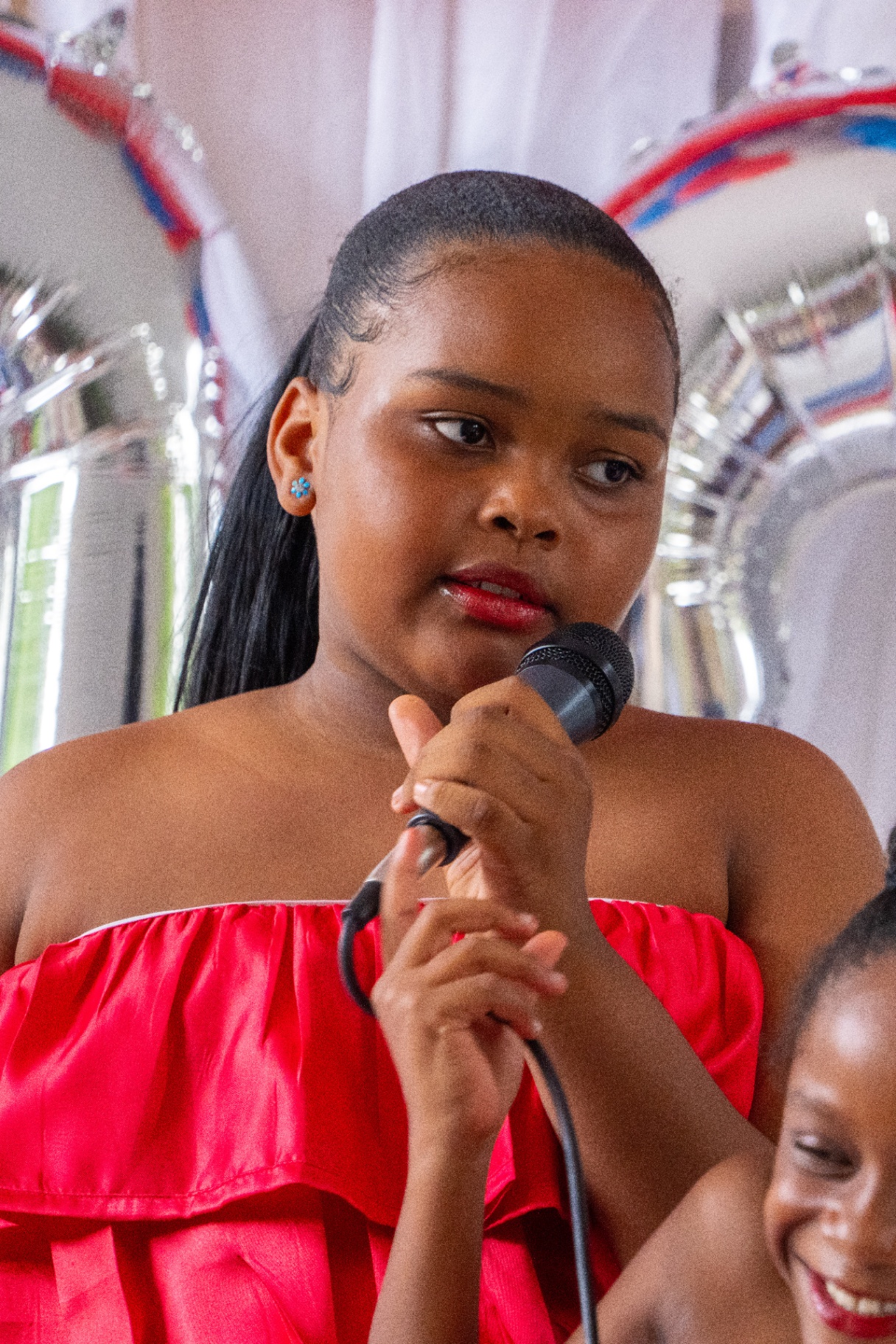 Student in red dress singing into microphone